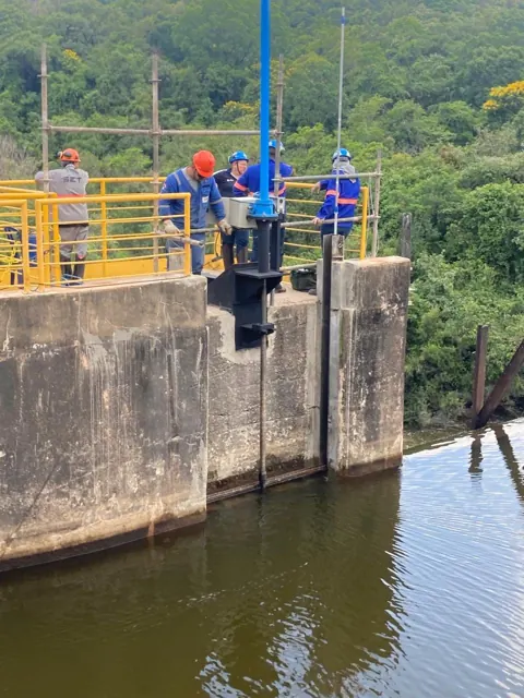 Diving team on a platform at a hydropower plant, beside the reservoir.