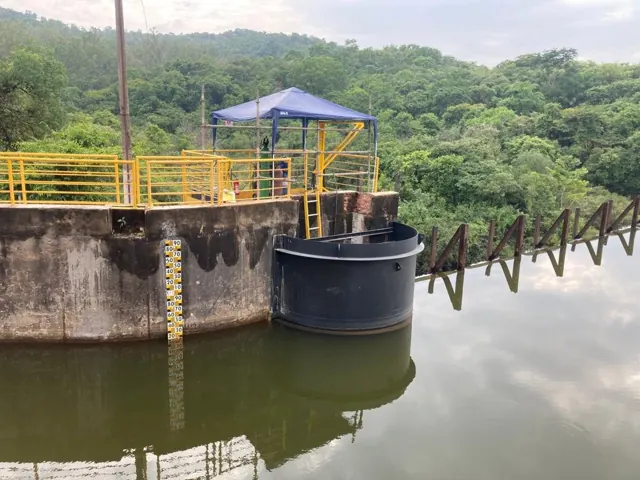 Intake structure beside a reservoir, with a walkway and guardrails.